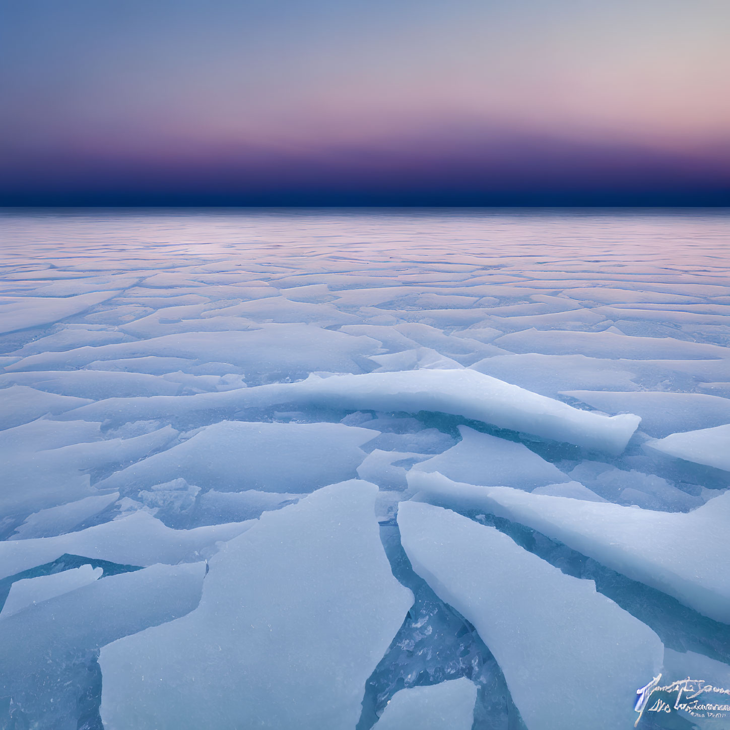 Twilight scene of broken ice sheets on frozen lake under gradient sky