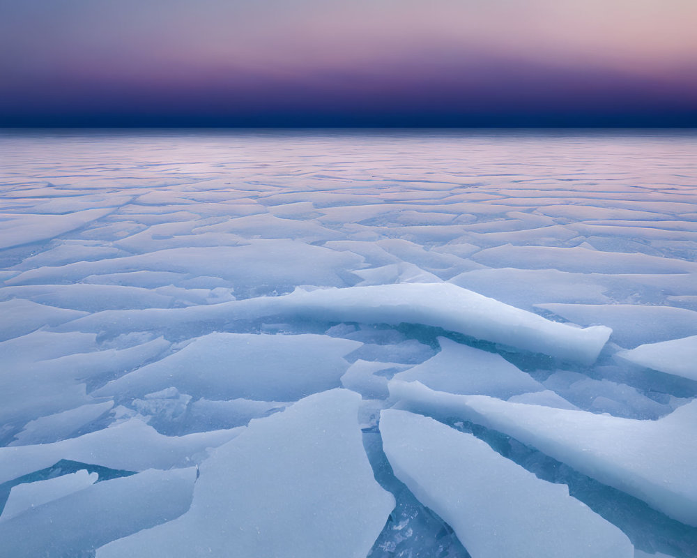 Twilight scene of broken ice sheets on frozen lake under gradient sky