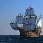 Tall ship with billowing sails on ocean under clear blue sky