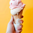 Swirled soft-serve ice cream with chocolate sauce and sprinkles on orange background