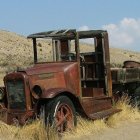 Classic Red Tanker Truck Parked on Grass with Clear Sky and Rock Formations