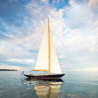 Colorful sailboat on calm waters with snowy mountains and bright sun