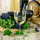 Elegant cheese and wine spread with grapes, candles, and glasses on table.