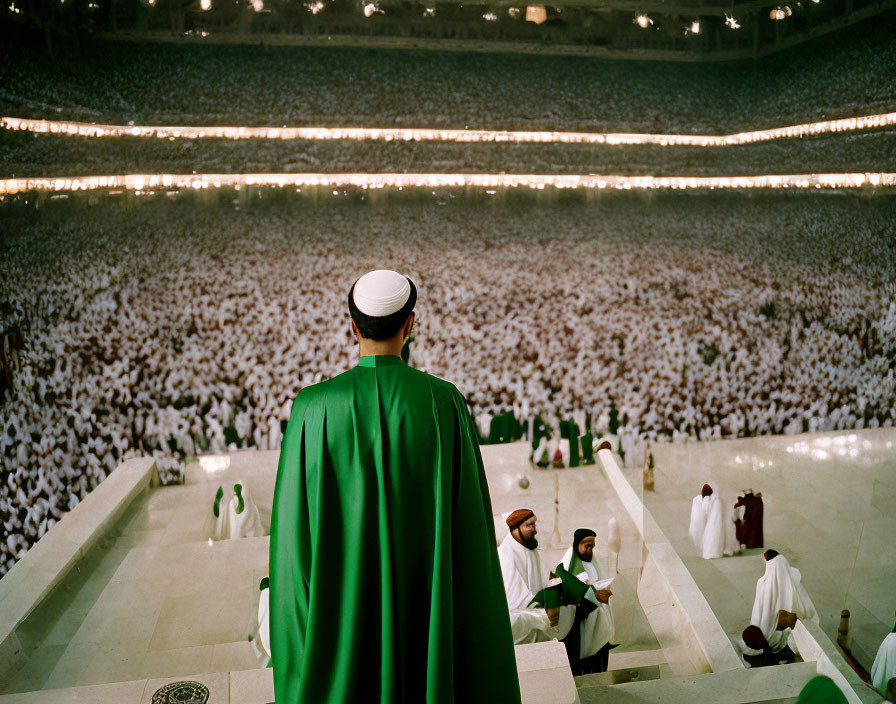 Man in Green Cloak Observing Crowd in Circular Venue