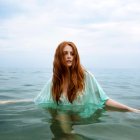 Redheaded Woman in Green Dress with Dragon in Misty Mountain Landscape