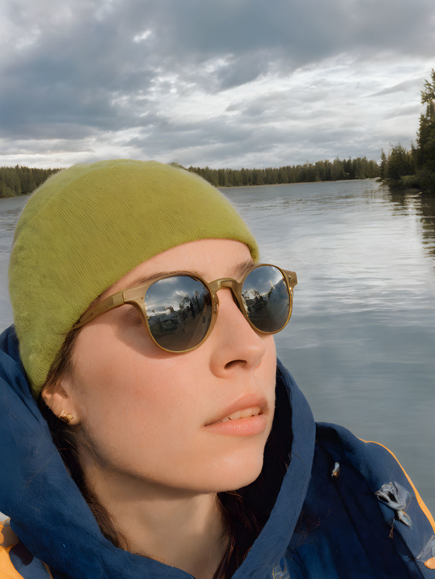 Woman in yellow beanie and sunglasses by serene lake