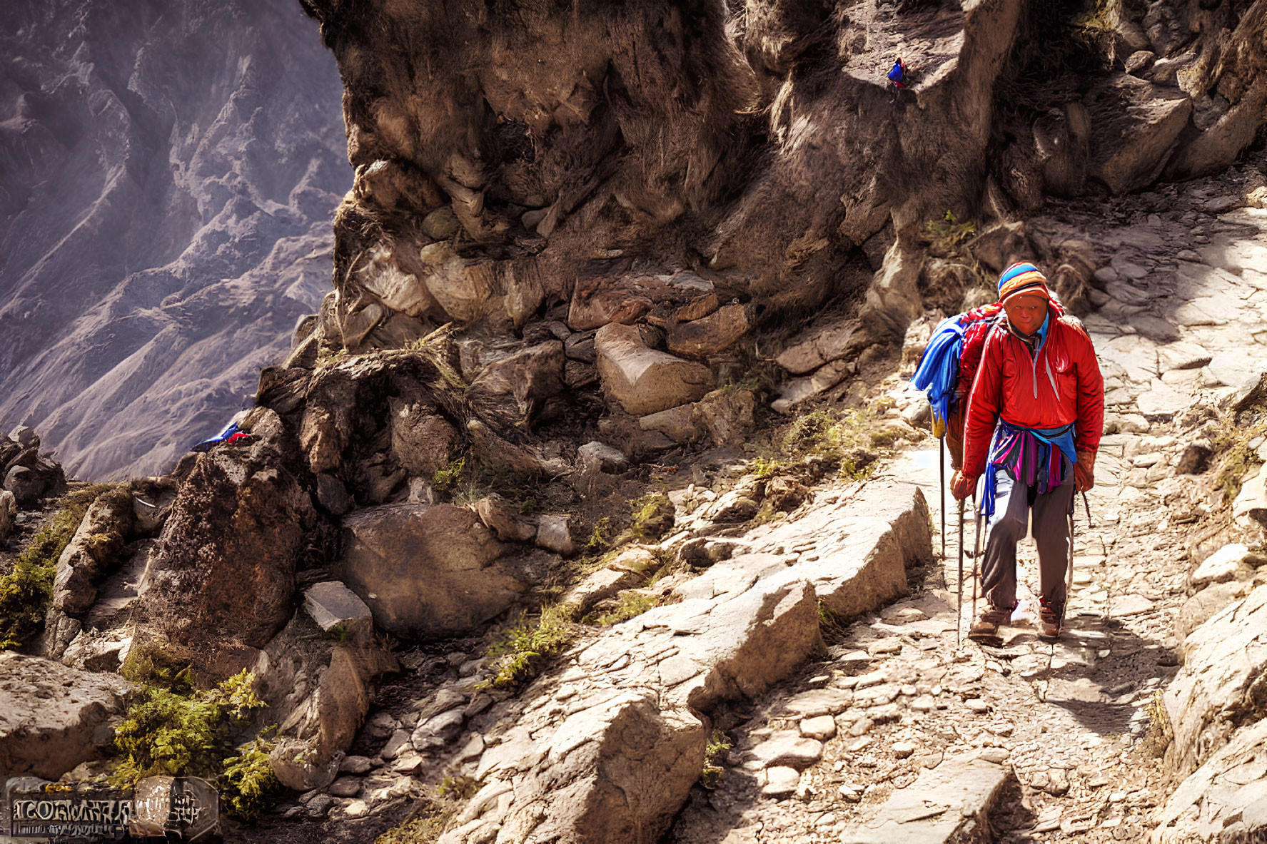 Hiker with blue backpack and walking poles on rocky mountain trail