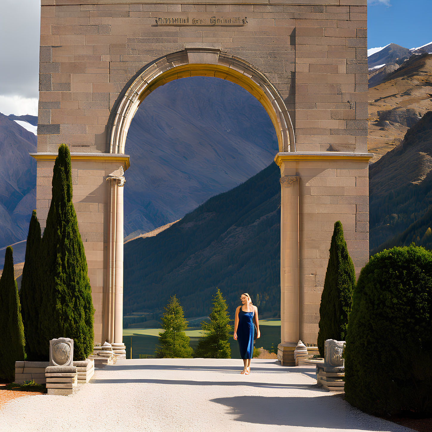 Woman in Blue Dress Walking Through Grand Archway with Cypress Trees and Mountain Vista