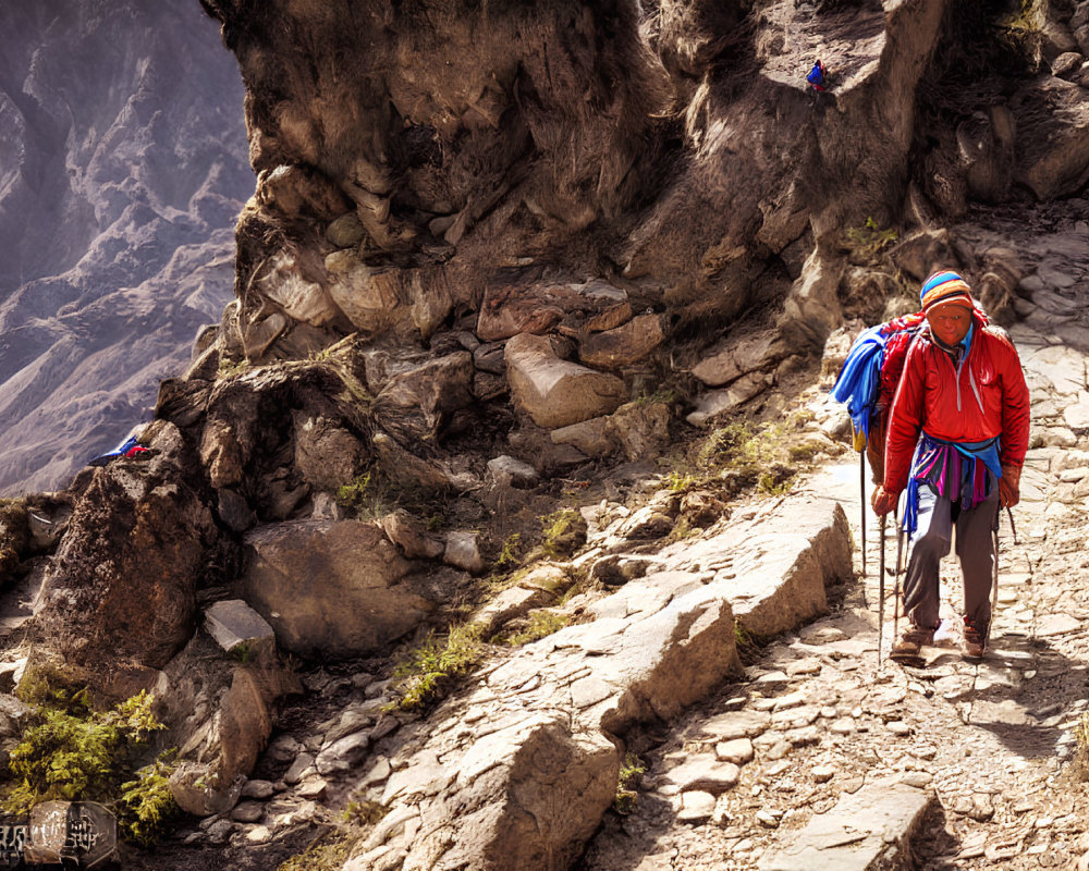 Hiker with blue backpack and walking poles on rocky mountain trail