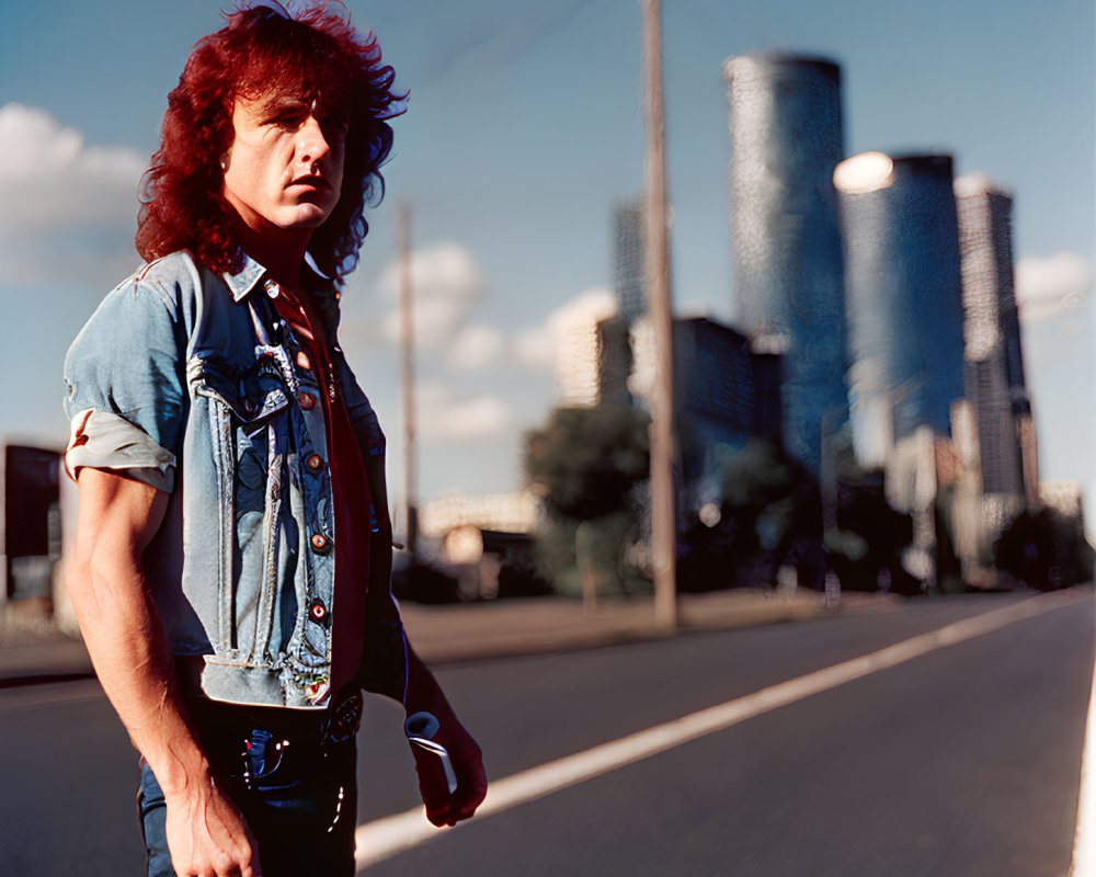 Red mullet hairstyle person in denim vest on city road with skyscrapers.