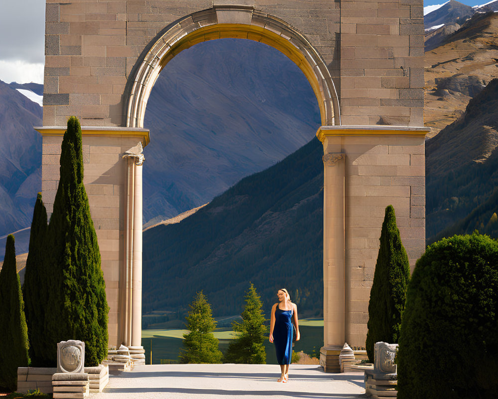 Woman in Blue Dress Walking Through Grand Archway with Cypress Trees and Mountain Vista