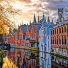 Scenic canal with traditional houses, boat, and flowers at sunset