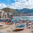 Vibrant beach scene with colorful domed structures, lush flora, and people enjoying seaside ambiance