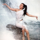 Woman in flowing white attire evokes freedom against textured background