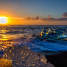 Colorful sunset landscape with cliffs, lake, vegetation, and crescent moon