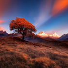 Vibrant landscape with orange-leaved tree, grassy hills, and snow-capped mountains at