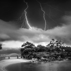 Stormy Black and White Landscape with Lightning over Water and Silhouetted Trees