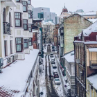 Snow-covered urban street with classic architecture and parked cars at twilight