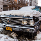 Vintage Black Car Covered in Snow on Street with Brownstone Buildings