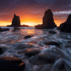 Vibrant sunset seascape with crashing waves and rocky formations