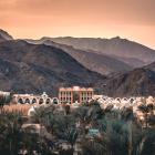 Ancient-style city in tropical valley with palm trees and classical architecture at sunset