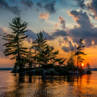 Tranquil landscape: cabin on islet, pine trees, calm waters, snow-capped mountains