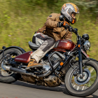 Person in leather jacket on fast modern motorcycle with motion blur on tree-lined road