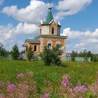 Blue dome church surrounded by wildflowers under sunny sky