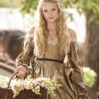 Blonde woman in golden dress with blue flower wreath in forest scene