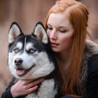 Red-haired person hugs Siberian Husky in snowy scene