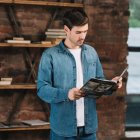 Man in Blue Ornate Uniform Reading Book in Dimly Lit Study