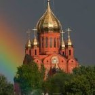 Golden-domed building with ornate details in greenery with flying birds