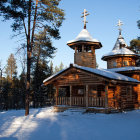 Snowy forest night scene with two wooden churches, moonlit interiors, and a figure approaching one.