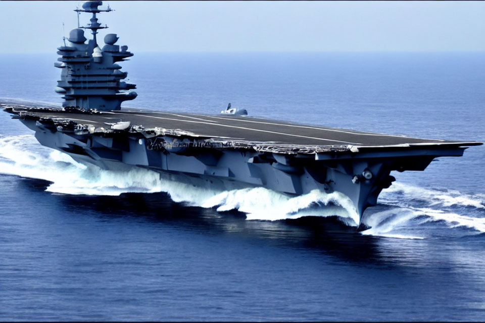 Military aircraft carrier with flight deck and island superstructure at sea