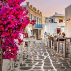 Charming alley with white walls, pink flowers, cobblestones, and blue balconies