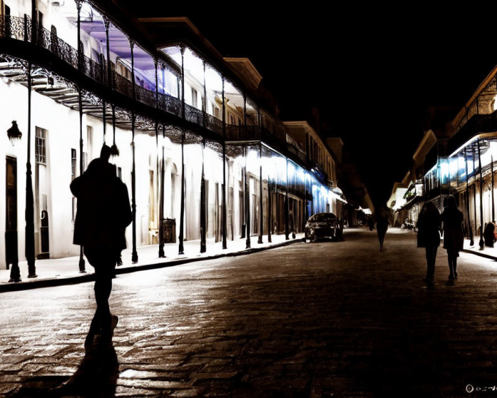 Nighttime Street Scene with Illuminated Buildings, Silhouette of Person, and Vintage Car