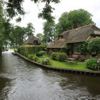 Serene fantasy landscape with thatched cottage, pond, flowers, stone bridge, boats, and lum