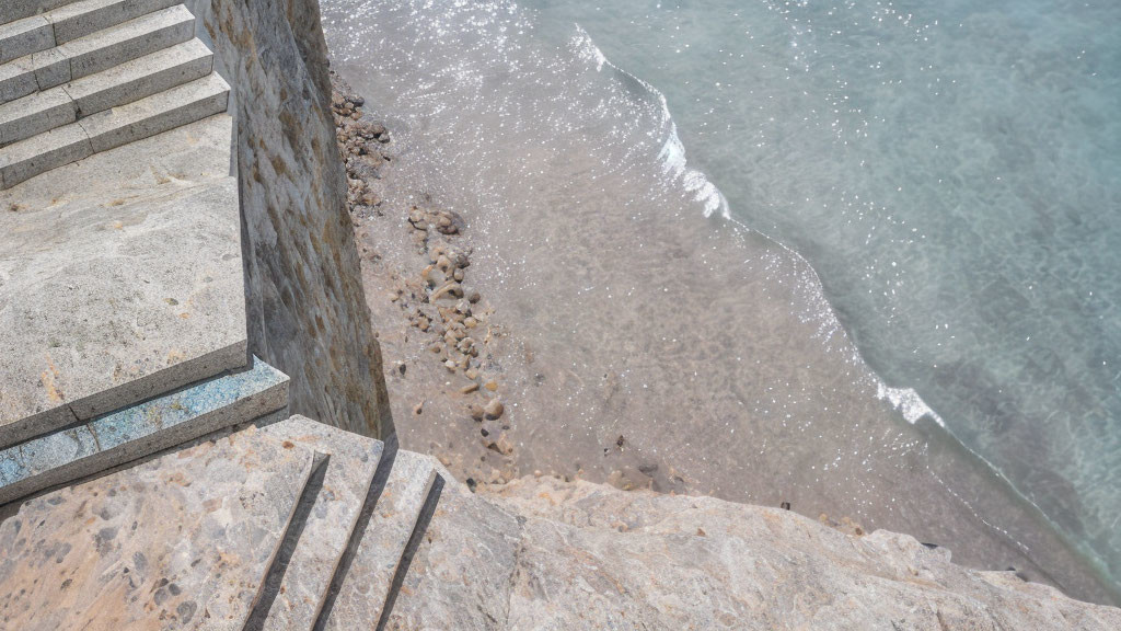 Rocky beach with concrete stairs and gentle waves.