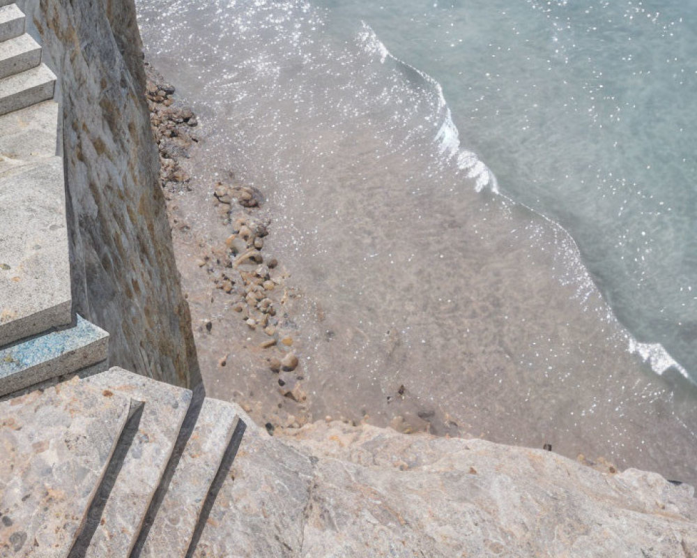 Rocky beach with concrete stairs and gentle waves.