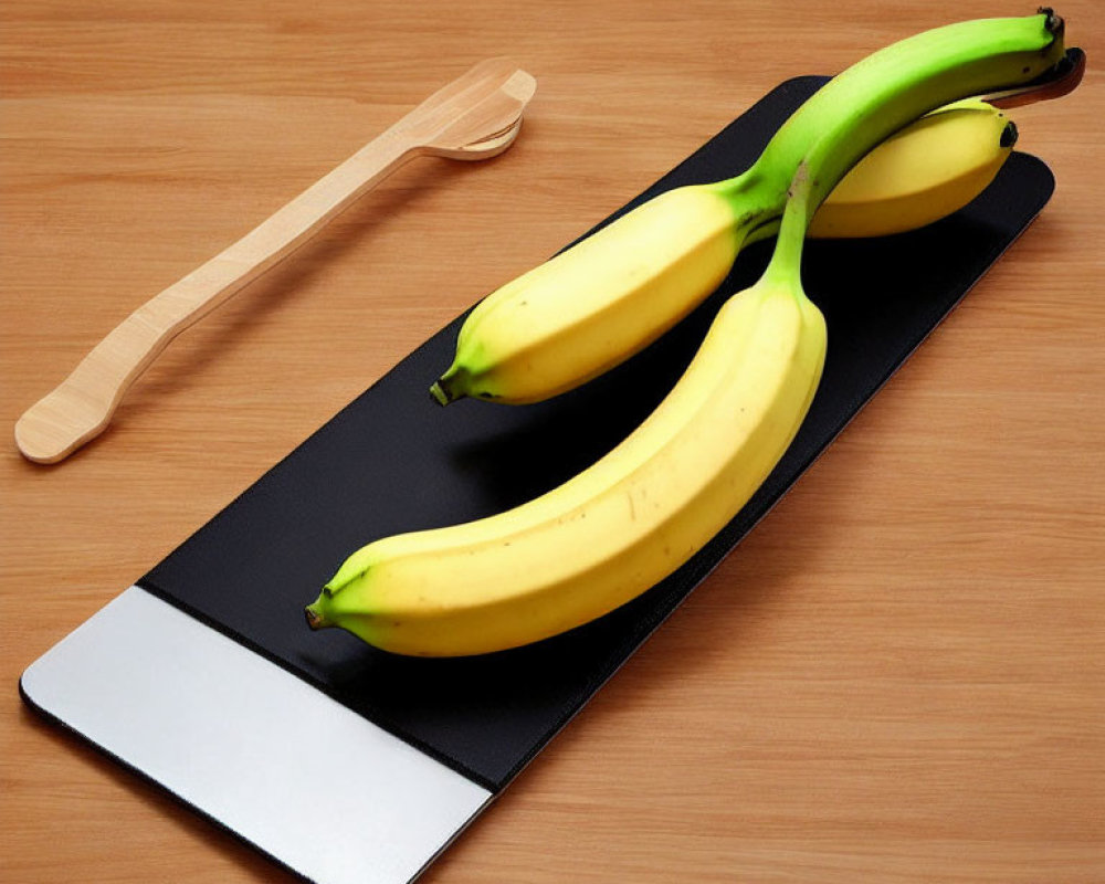 Bananas on Black Placemat with Wooden Spoon on Table