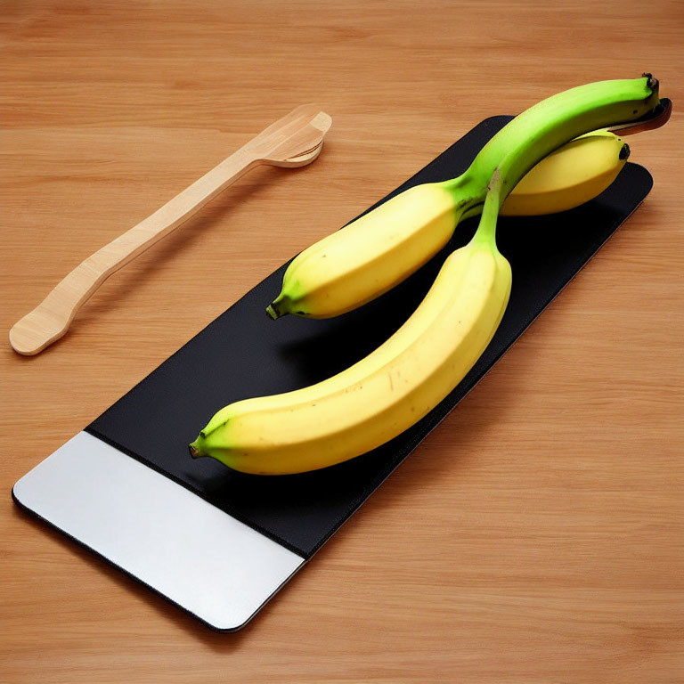 Bananas on Black Placemat with Wooden Spoon on Table