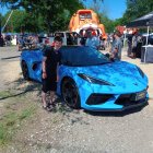 Futuristic blue sports car in urban square with telescope and bystanders