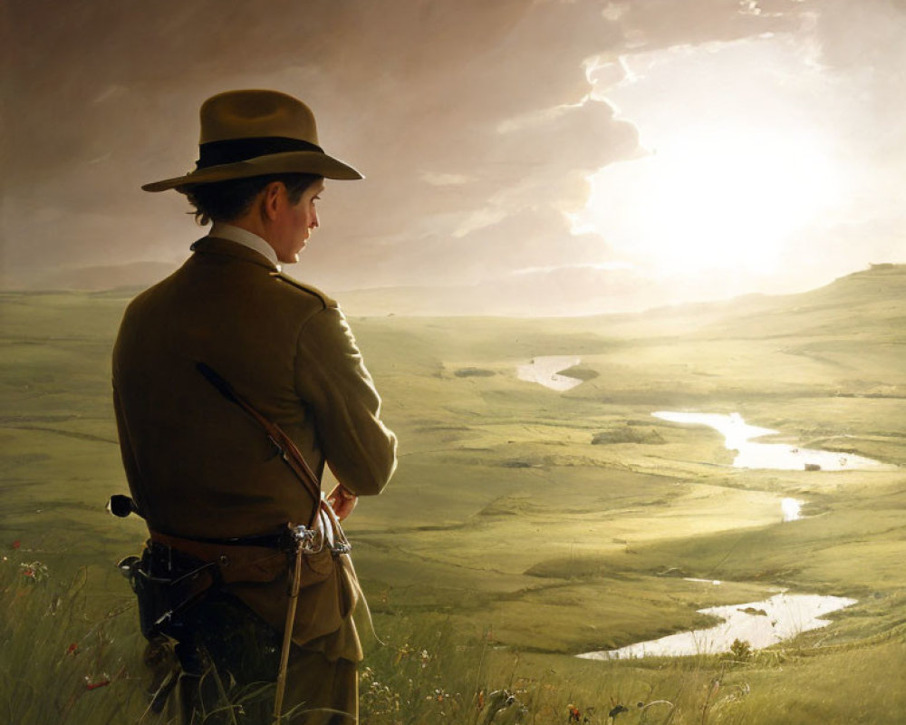 Person in hat and coat in lush field at sunset with winding river and dramatic sky