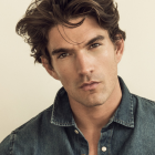 Detailed portrait of young man with curly hair and intense eyes in denim jacket