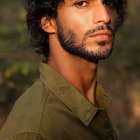 Pensive man painting with vibrant smudges on face and shirt