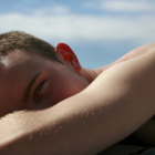 Young person with curly hair resting by serene ocean