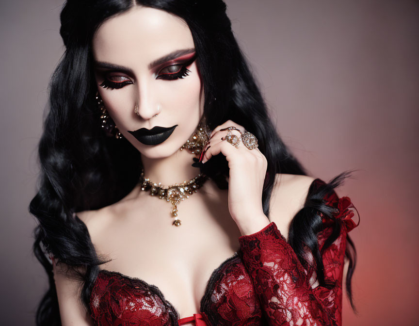 Dramatic makeup and gothic jewelry on person against pink background