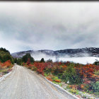 Rural landscape with dirt road, barn, hills, and fog