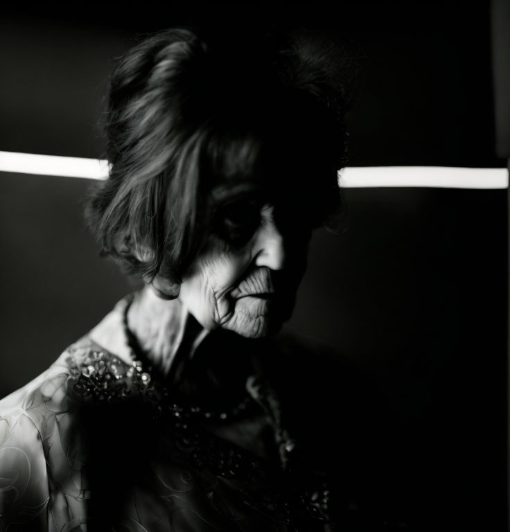 Elderly woman with dark hair in decorated attire on dark background