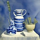 Striped blue and white jug, patterned vase, bowl with green plants on draped table against blue